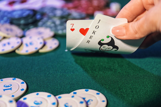 Female hand with playing cards and chips on table in casino