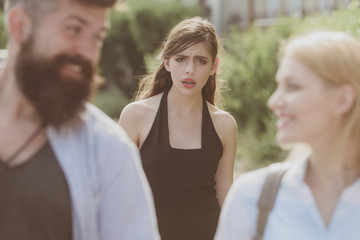 She is the jealous type. Jealous woman look at couple in love on street. Unhappy girl feeling jealous. Romantic couple of man and woman dating. Bearded man cheating his girlfriend with another woman - obrazy, fototapety, plakaty