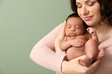 Portrait of happy mother with little baby on color background