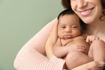 Portrait of happy mother with little baby on color background