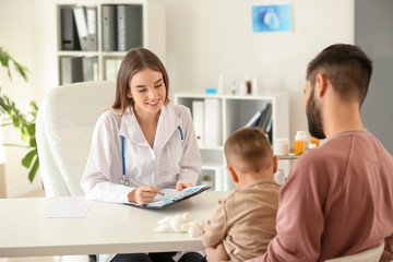 Fototapeta premium Young father with his little son visiting doctor in clinic