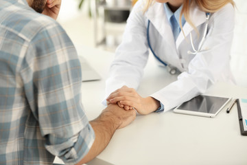 Female doctor calming male patient in clinic