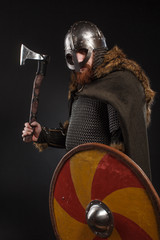 Naklejka premium Warrior Viking in full arms with axe and shield on dark background