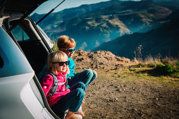 happy kids travel by car in mountains