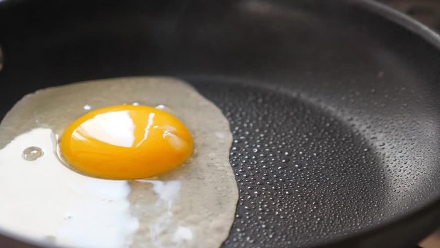 Pouring egg on frying pan. Cooking fried eggs, closeup