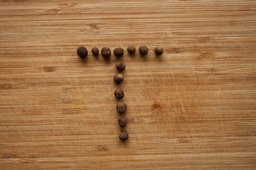 Capital characters made of peppercorns. Alphabet letters on wood background.