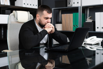 Fototapeta premium Portrait of young man sitting at table in office