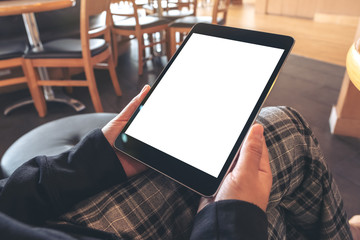 Mockup image of a woman holding black tablet pc with blank white screen while sitting in cafe