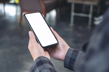 Mockup image of hands holding black mobile phone with blank white desktop screen