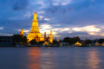 Naklejka premium Wat Arun Temple Beside Chao Phraya River with Beautiful Sunshine Through the Cloud, Bangkok, Thailand. One of the Most Famous Place of Thailand's Landmarks. 