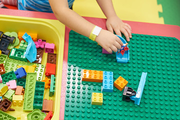 child playing and building with colorful plastic bricks table. Early learning and development.