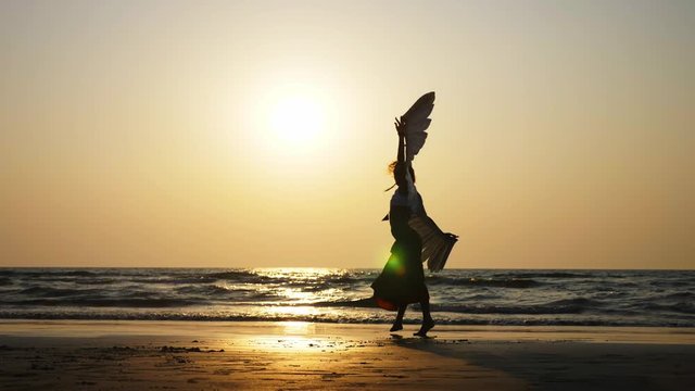 Silhouette of young girl with angel wings dancing at sunset in slow motion