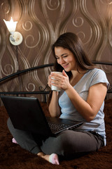 Naklejka premium Casual beautiful woman working on a laptop sitting on the bed i