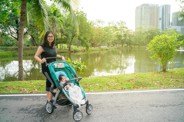 Mother with baby infant recreation in green park with stroller