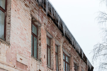 Icicles hanging from the roof of an old brick building