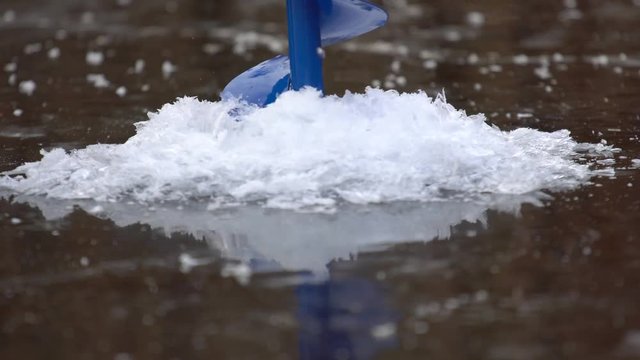 Fisherman drills ice with a drill