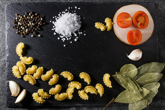 Whole grain raw Italian pasta and ingredients composition on black rustic slate stone background, top view with copy space © loki_ast