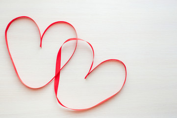 Two red ribbons shaped as heart on wood table