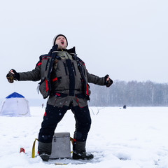 Happy shouting adult fisherman after successful winter fishing at cold winter day
