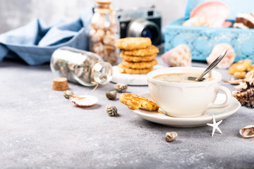Cup of coffee and biscuits with seashells and decorations. Dreams of sea vacation and concept. Copy space.
