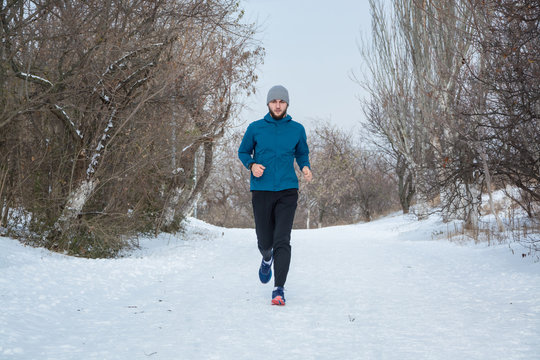 Young male runner training outdoors in winter times, man run on the snow  - Powered by Adobe