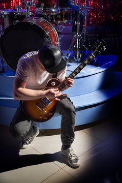 Guitarist in a baseball cap playing music on the electric guitar