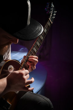 Guitarist in a baseball cap playing solo on the electric guitar