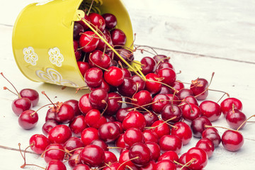 Sweet red fresh cherries in a bucket on a grunge wooden table