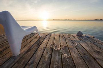 Naklejka premium Landscape with empty chair in wooden footbridge on Powidzkie Lake in Poland.