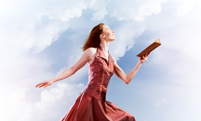 Fototapeta na wymiar Girl against cloudy sky with opened book in palm as idea for knowledge