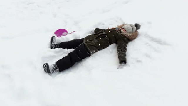 Little girl making snow angel.Kids winter activities concept