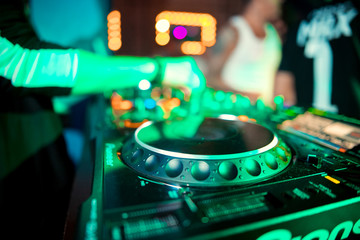 DJ console cd mp4 deejay mixing desk Ibiza house music party in nightclub with colored disco lights.