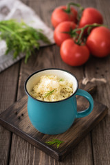 Couscous with butter, fresh herbs and tomatoes in a cup on a wooden table for lunch