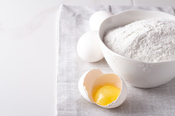 flour and raw chicken eggs on a white background.