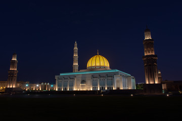 Sultan Qaboos Grand Mosque, Muscat, Oman during the early evening hours in the dark blue sky of sunset showing off the glowing dome.