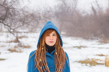 Young woman in retro blue coat walk in the foggy park in the winter times, snow and trees background,fantasy or fairy concept