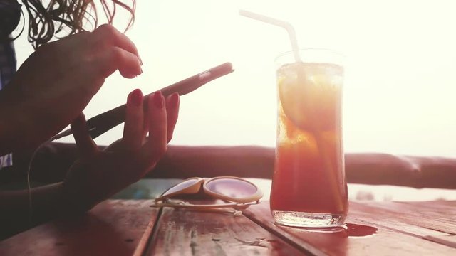 Female tourist enjoying rest on beach cafe during sunset chatting via mobile. 3840x2160