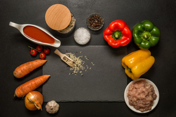 Flat lay, top view. Close up. Bright multicolored ingredients for baking stuffed bell peppers. Black background. Copy space.