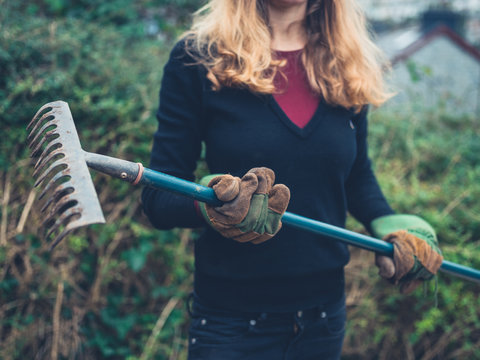 Young woman with rake in garden