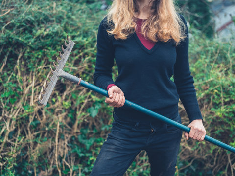 Young woman with rake in garden