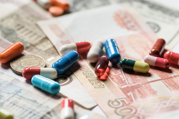 selective focus of colorful pills on banknotes background