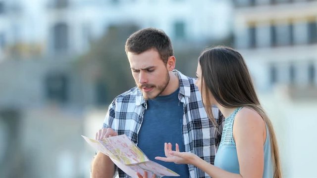 Angry couple of tourists arguing about location checking map on vacation