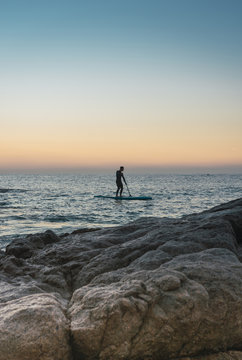 Man practicing paddle surfing with neoprene in a sunrise
