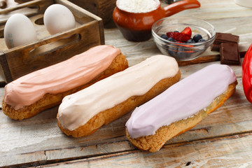 eclairs with different fillings on wooden background