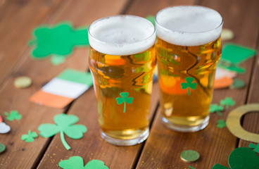 st patricks day, holidays and celebration concept - two glasses of draft light beer and party props on wooden table