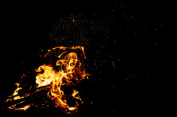 Burning woods with firesparks, flame and smoke. Strange weird odd elemental fiery figures on black background. Coal and ash. Abstract shapes at night. Bonfire outdoor on nature. Strenght of element.