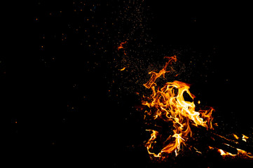 Burning woods with firesparks, flame and smoke. Strange weird odd elemental fiery figures on black background. Coal and ash. Abstract shapes at night. Bonfire outdoor on nature. Strenght of element.