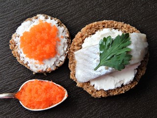 Elegant canapes with cream cheese, herring and flying fish caviar and flying fish caviar in vintage spoon