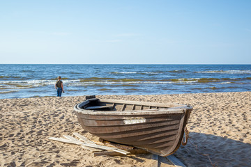 Wooden boat on the coast of the Baltic Sea. The girl looks into the distance.