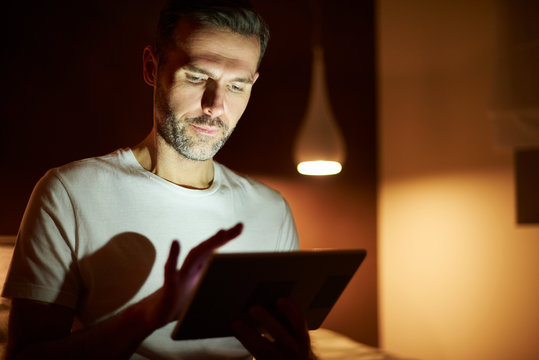 Focused man using tablet at night - Powered by Adobe